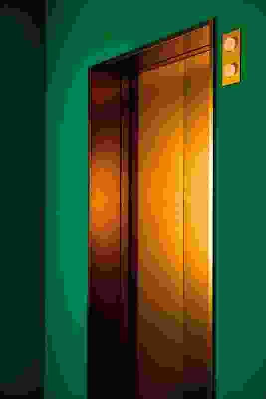 The gilded elevator doors open at the ninth floor to reveal emerald green walls.