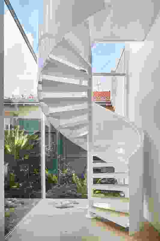 A glass-enclosed spiral stair forms the heart of the plan from which the main rooms unfurl.
