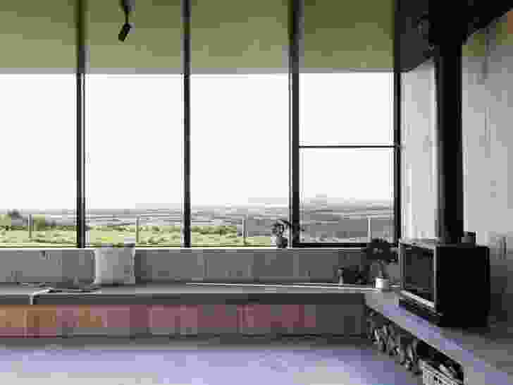 A bench seat lines the perimeter of the living area and the black formply ceiling reflects the colours of the surrounding landscape.