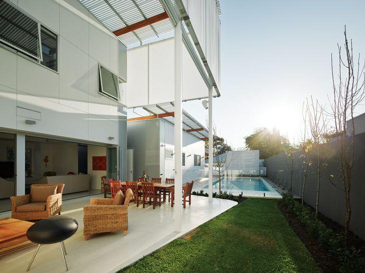 A double-height outdoor room mediates the temperature of both the upper and lower levels, with automatic blinds shading the house.