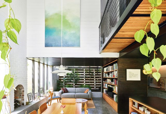 A double-height volume rises over the dining table, filling the depths of the lower level with northern light. Artwork (L-R): Jordy Hewitt; Laura Patterson.