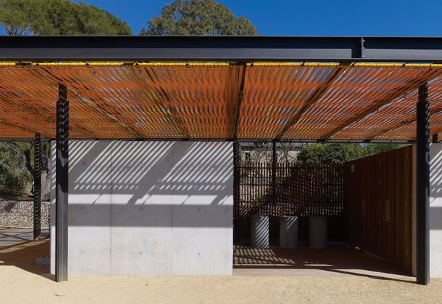 A solid concrete wall and tall doors of timber slats form the toilet pavilion.