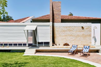 An open-air brick fireplace at the end of the garden sits adjacent to a swimming pool.