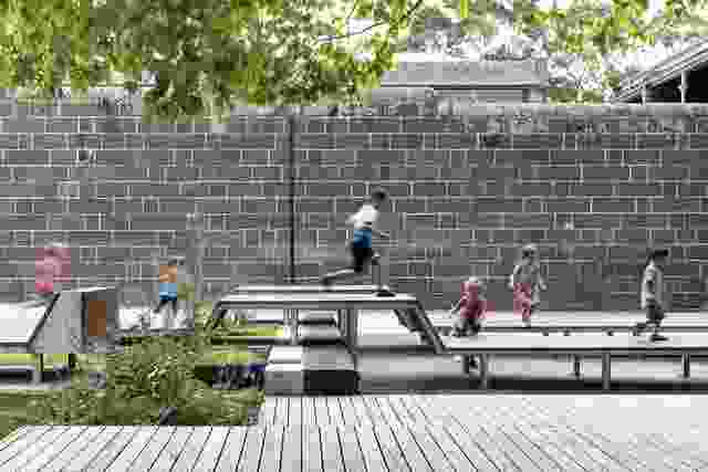 Children clamber over timber platform seating against the formidable bluestone-wall backdrop of Pentridge Prison’s former mustering yard.