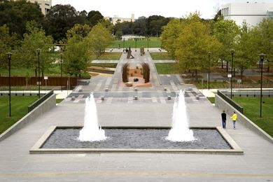 The campus and Reconciliation Place viewed from the NLA podium. Questacon is visible on the right and the NGA view corridor is revealed through the removal of Enid Lyons Street and transplanting of some 30 mature Plane Trees. The NLA water feature was restored to match its former glory. 