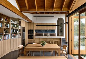Built-in timber bookshelves that edge the living and dining room are accented by exposed chalk-toned brick.