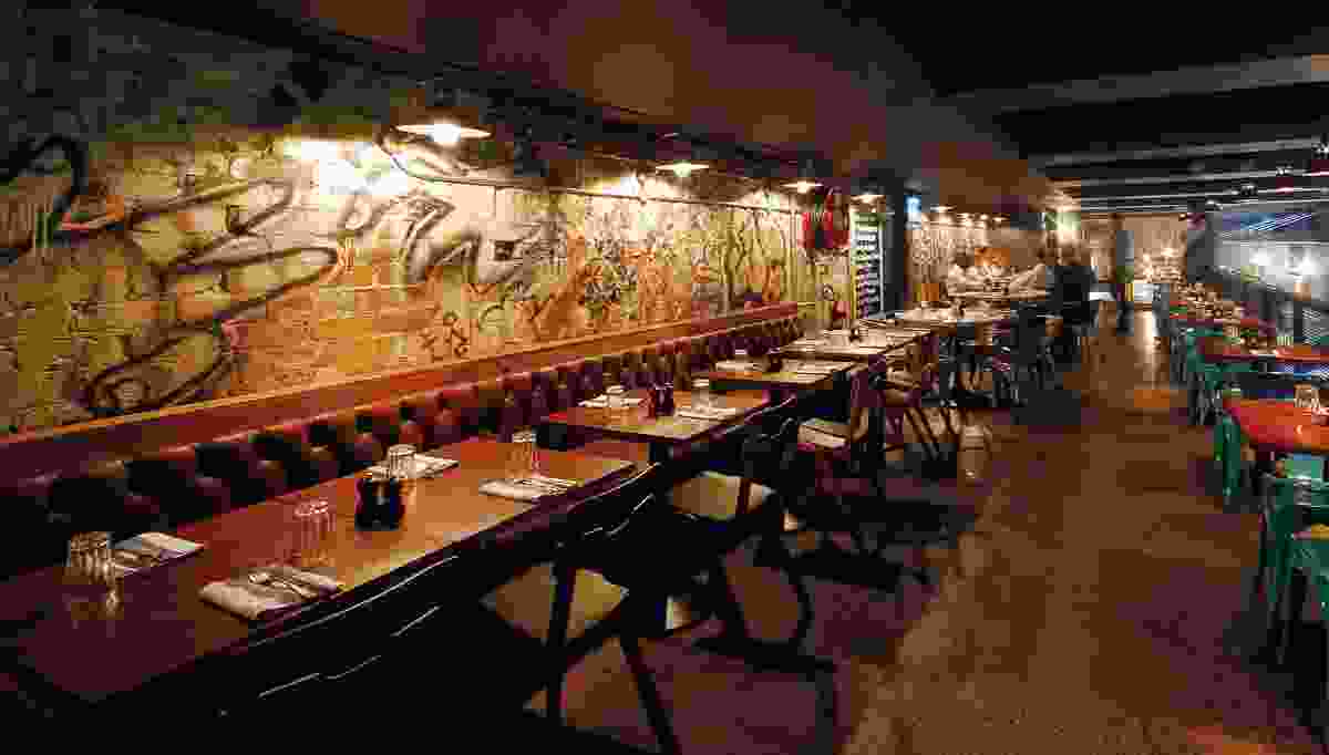 The mezzanine level features a rough brick wall with graffiti behind a banquette.