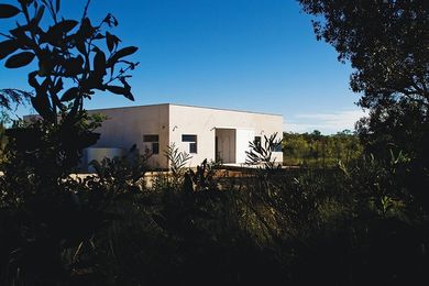 The Diamond Beach House curls “itself like an armadillo around an enclosed courtyard” with brick walls rendered to look more like concrete.