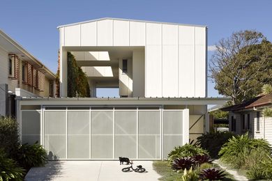 From the street, a gable roof and fence-like perforated garage panels suit the suburban locale.